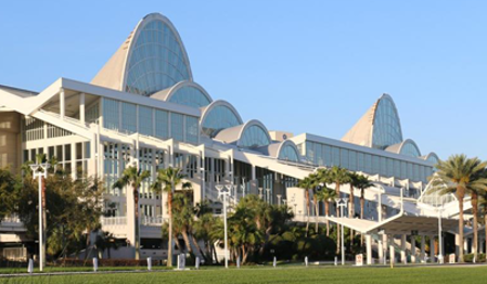 Large modern convention center with glass arches and a green lawn.